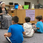 Thumbnail from still of video showing teacher seated in chair in front of children seated on the floor